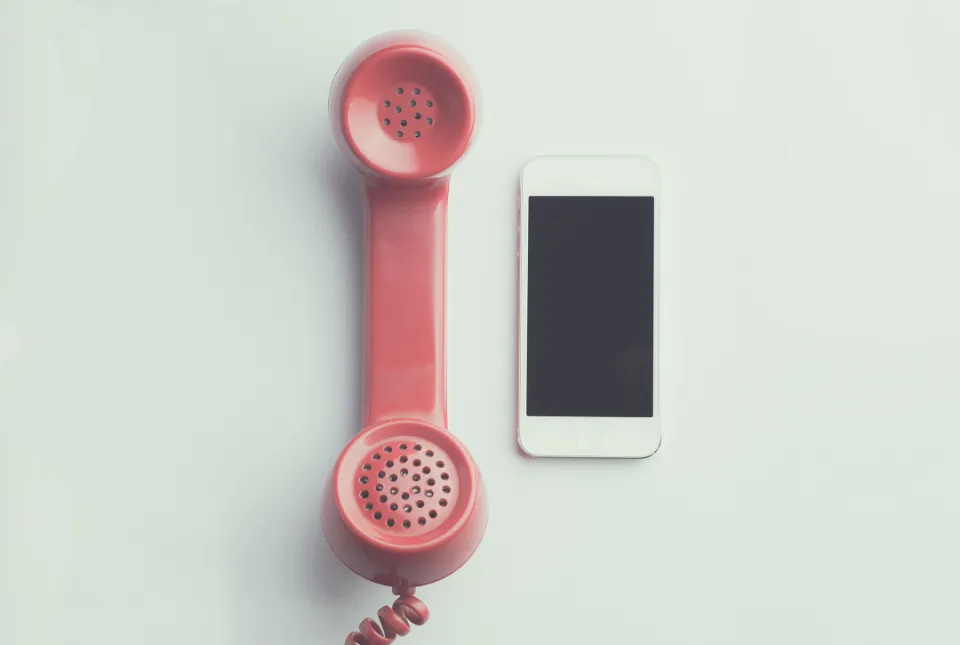 Un combiné rétro rose posé à côté d’un smartphone