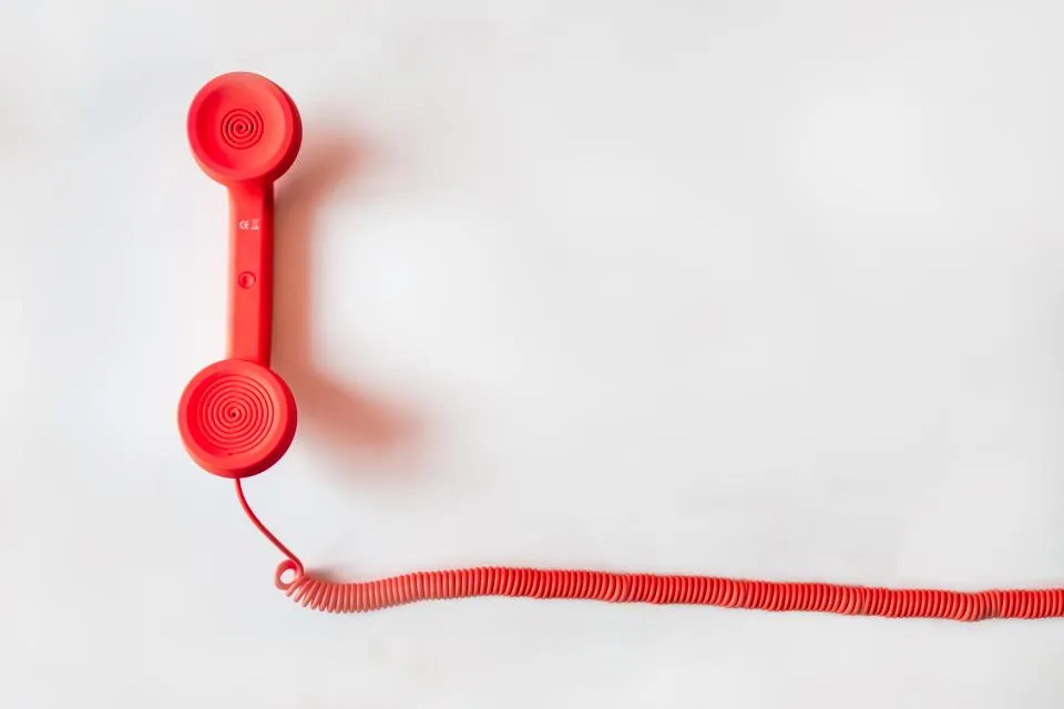 Un combiné de téléphone rouge et son fil torsadé